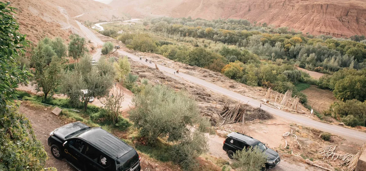Xped Global: two branded expedition vehicles overlooking a mountain valley.